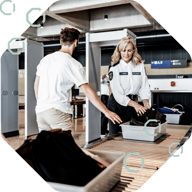 Security officer screening passenger and luggage at airport security checkpoint