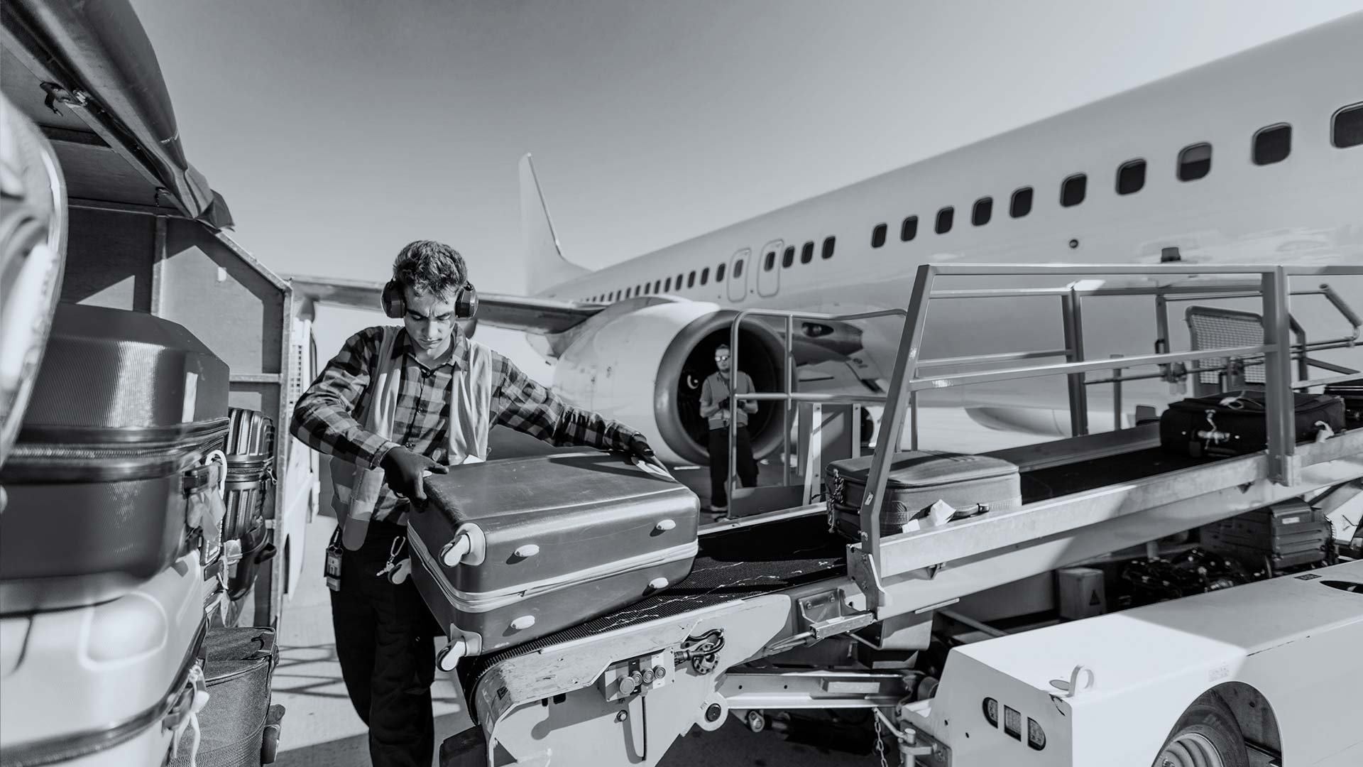 Baggage handler loading a suitcase onto an aircraft