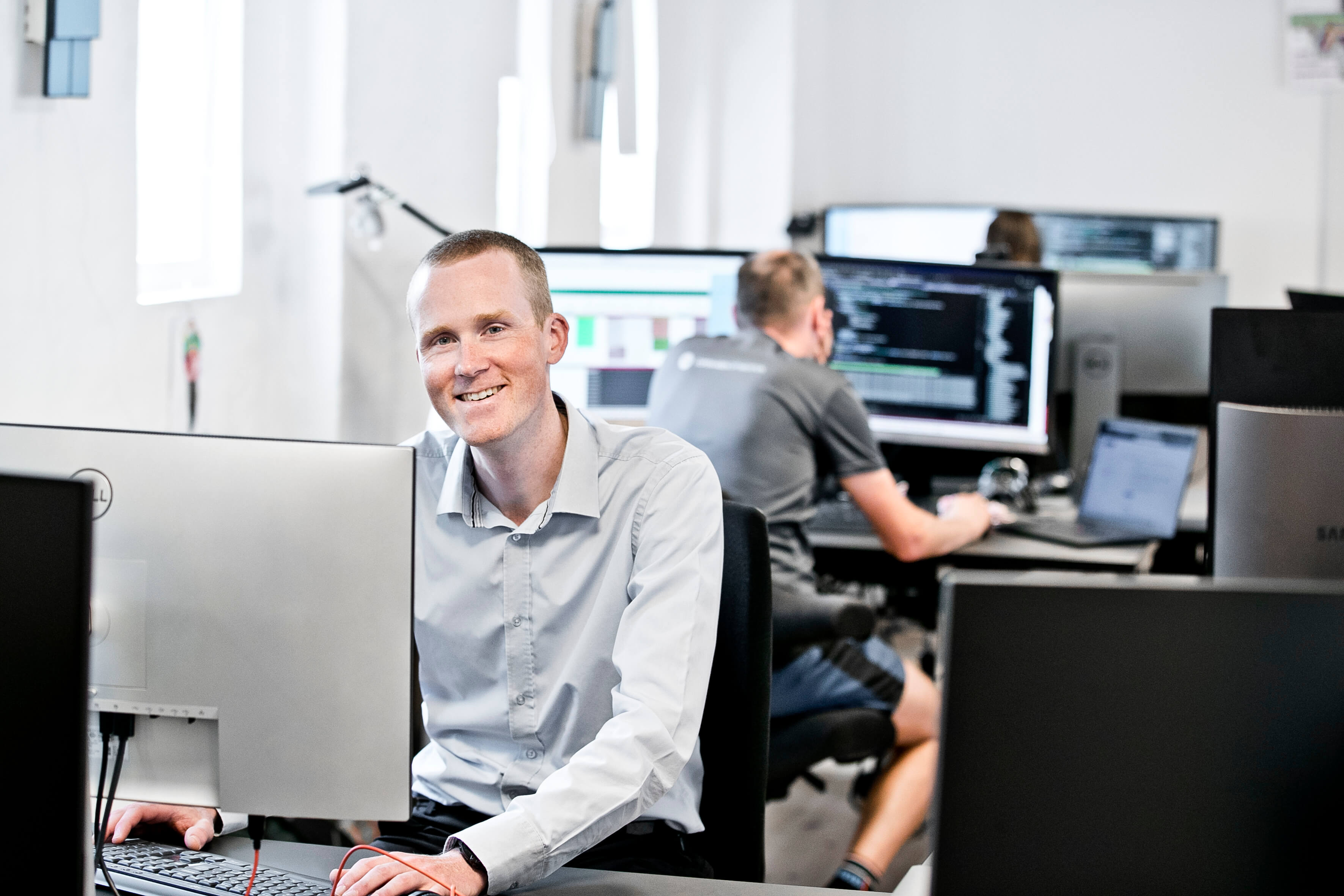 A software developer by his desk, smiling